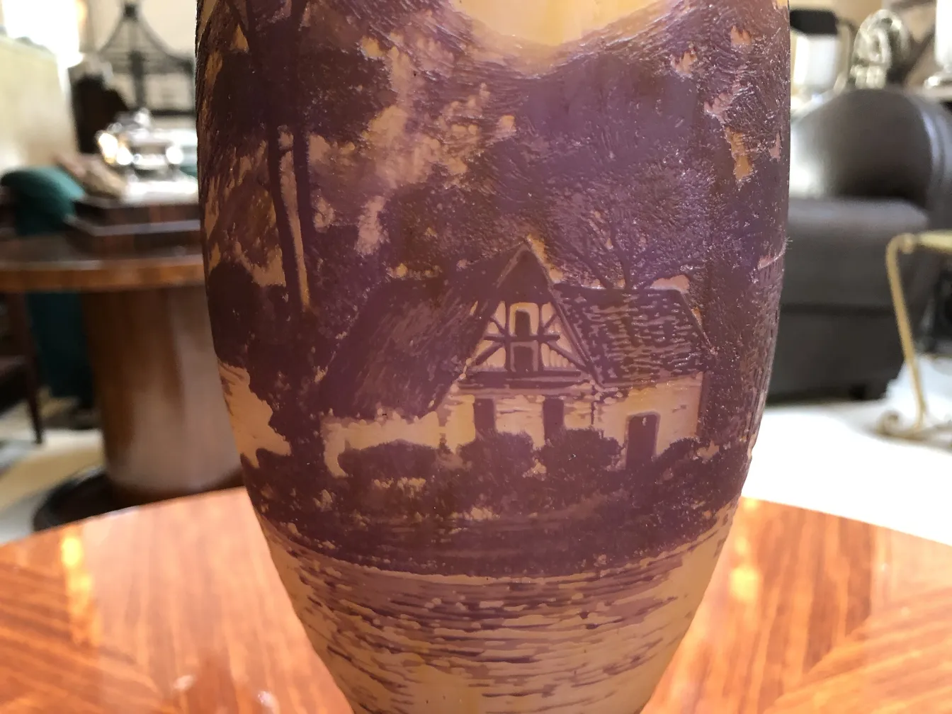 Detalle de vidrio antiguo firmado, con paisaje y casa. Fondo claro.