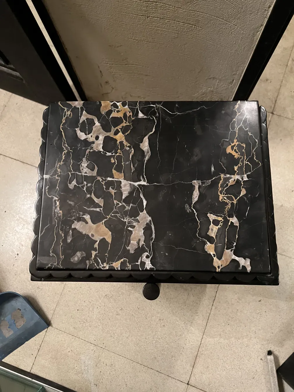 Ancienne table de chevet avec surface décorative et détails uniques, dans un cadre classique et confortable.