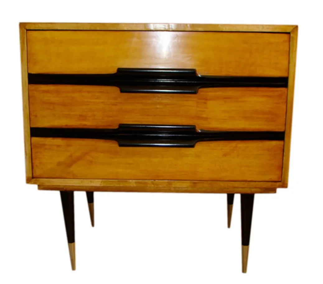 طاولة نوم قديمة مع درجين وأرجل سوداء، في بيئة دافئة.