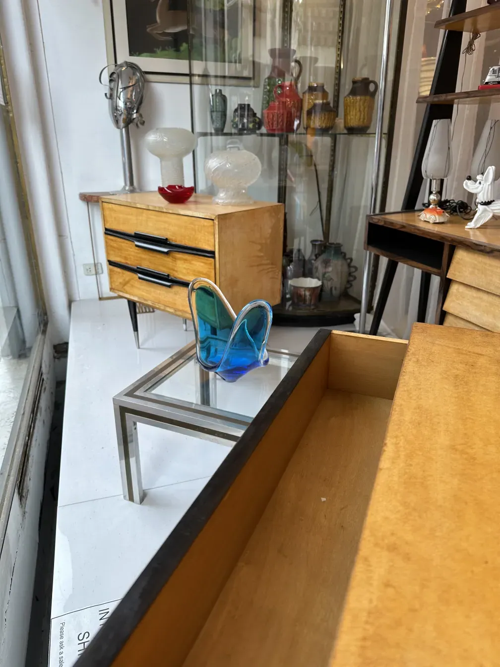 Table de chevet antique avec tiroirs et vaisselle colorée.