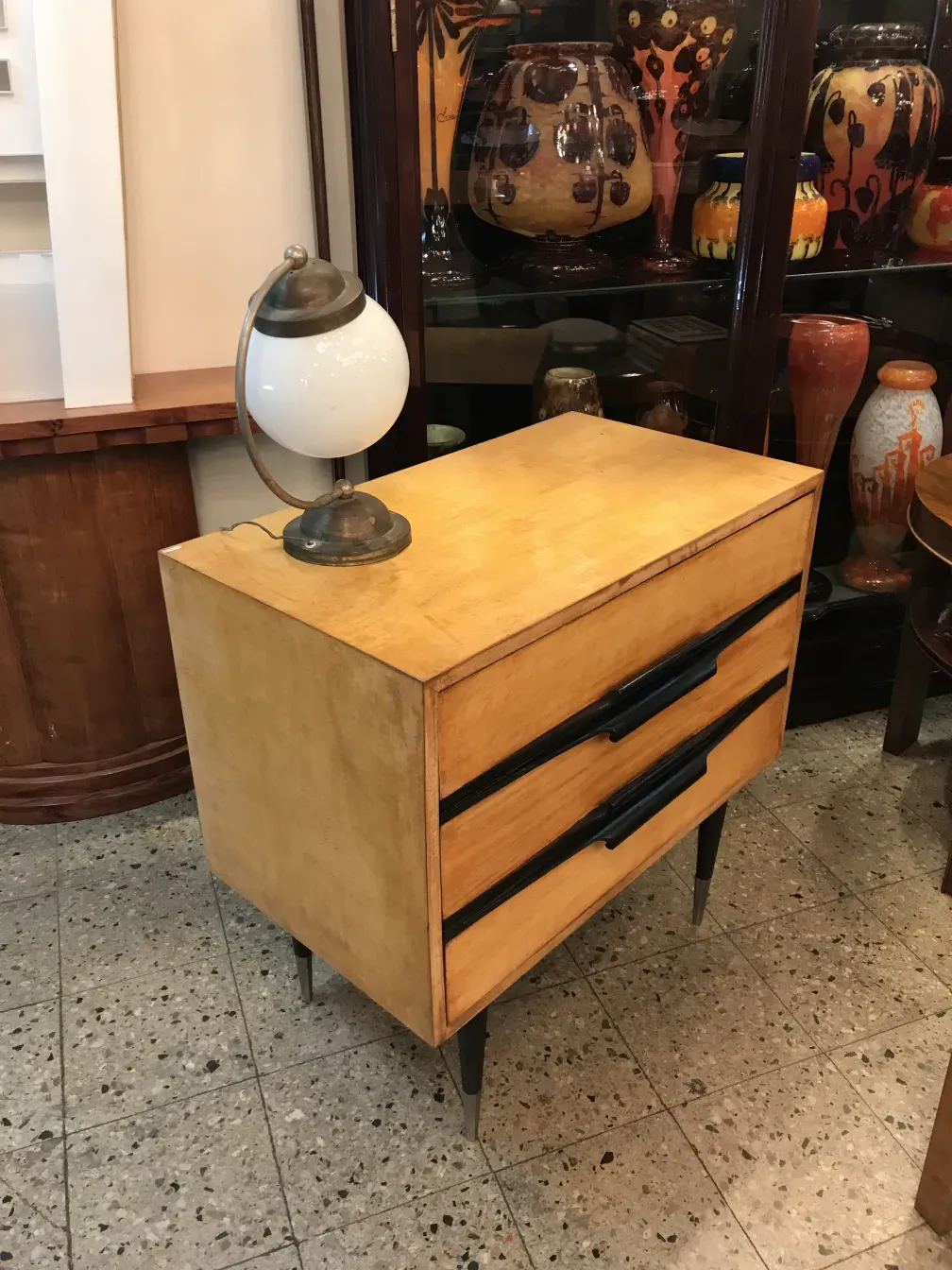 mesa de luz antigua con cajones y lámpara decorativa, ambiente con jarrones de cerámica