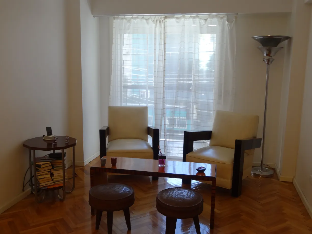 mesa ratona antigua en una sala con sillones y luz natural