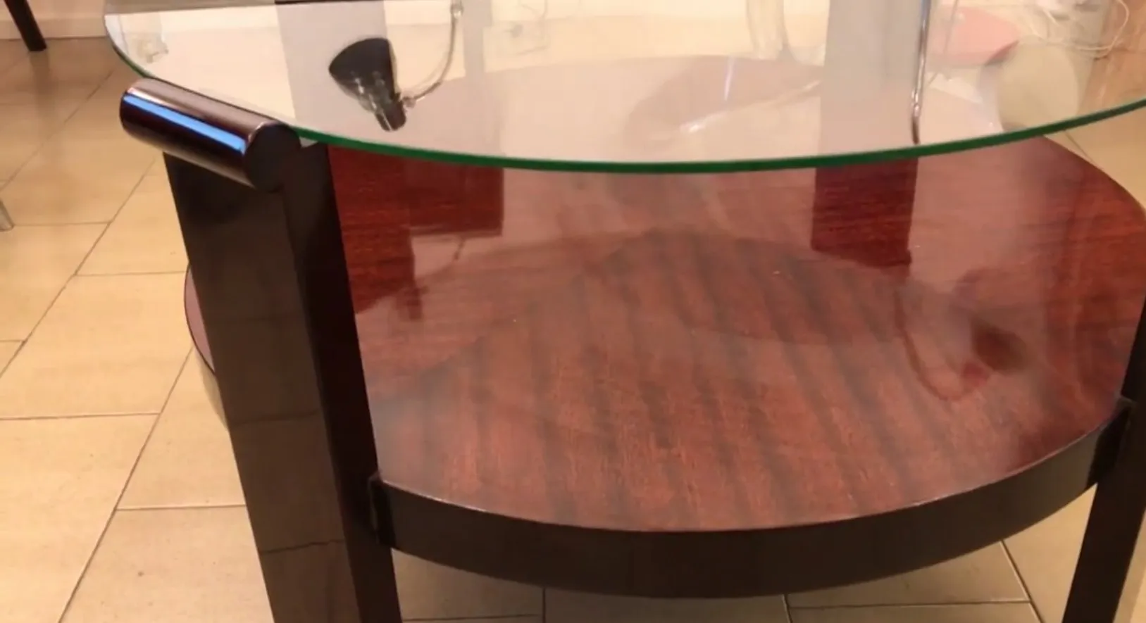 mesa de centro antiga redonda com base escura e tampo de vidro