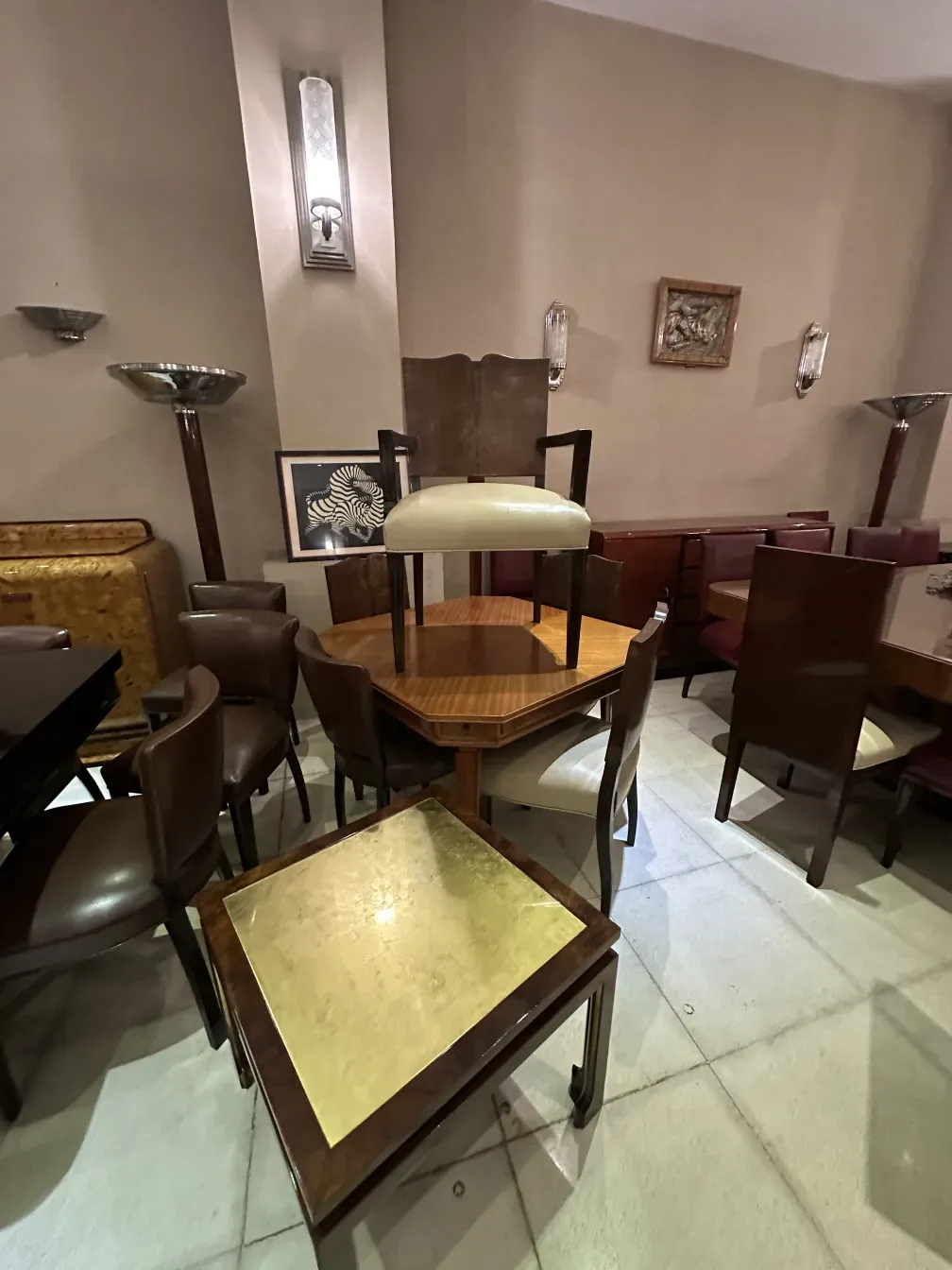 mesa ratona antigua con superficie dorada, rodeada de sillas