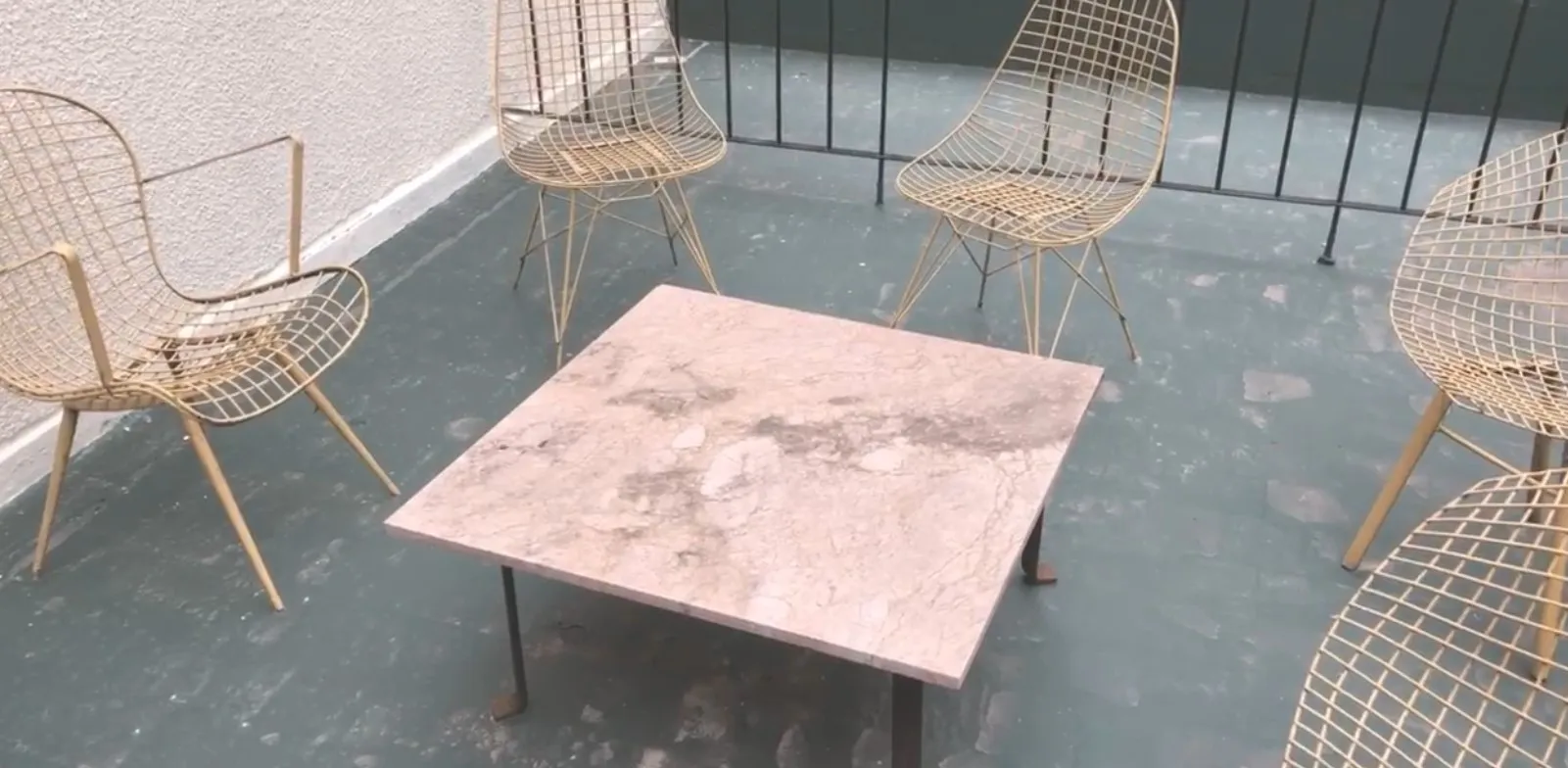 mesa de centro antiga em um ambiente moderno com cadeiras douradas