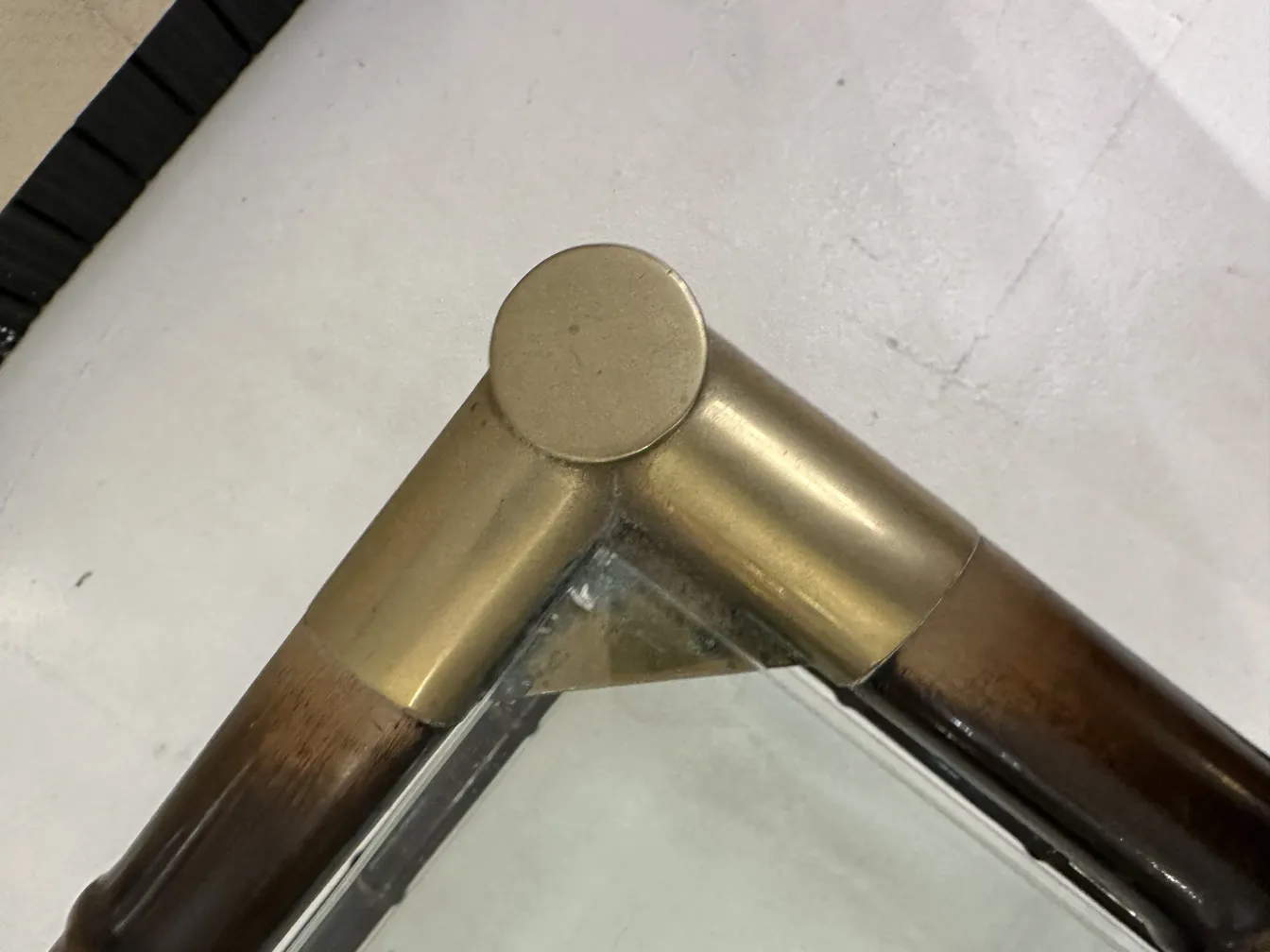 Detalle de una esquina de una mesa ratona antigua con acabado dorado y madera.