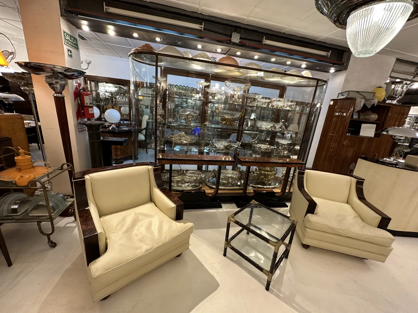 Antique coffee tables in a living room with chairs and decorative display cases.