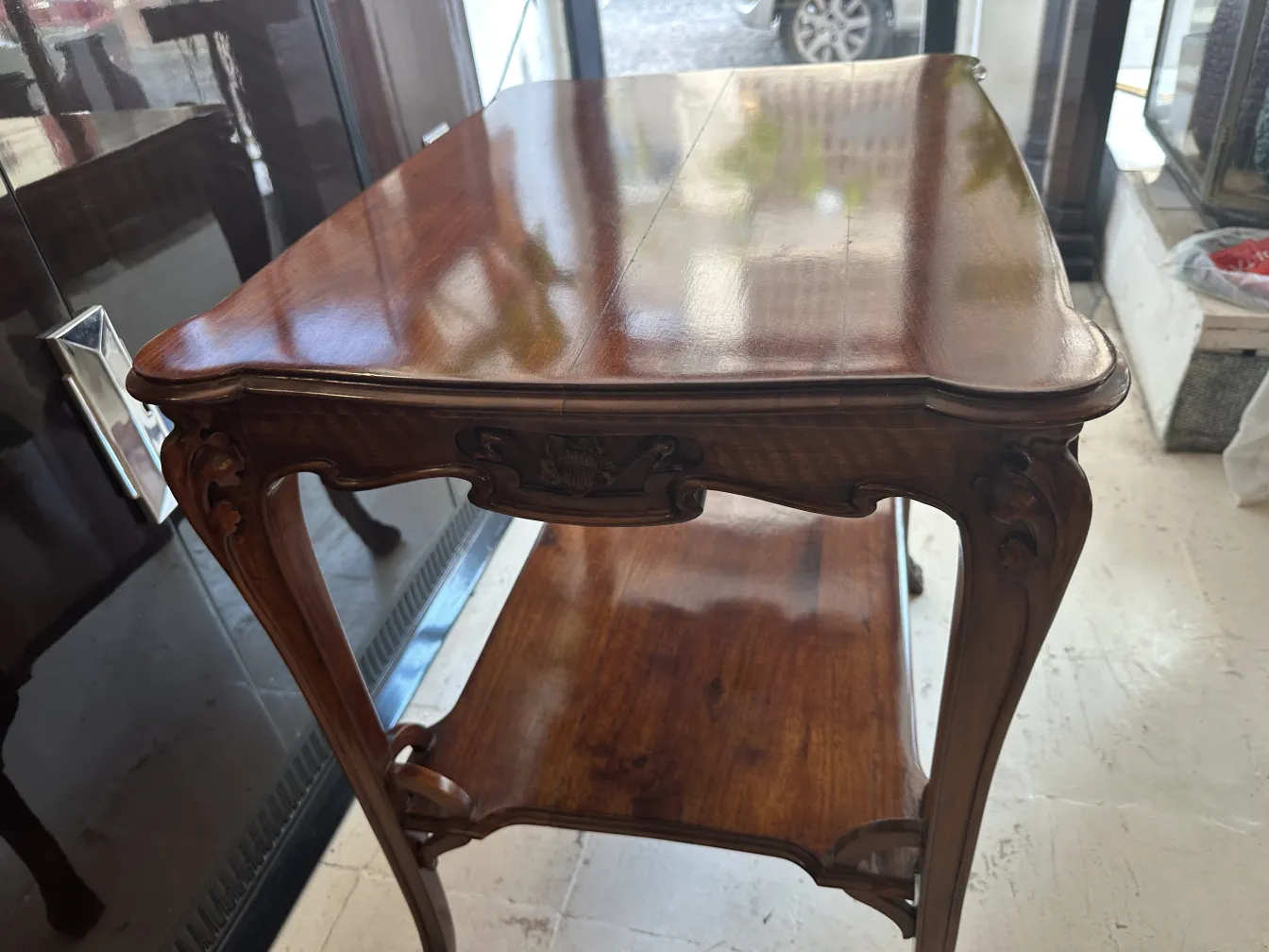 Petite table ancienne de style Art Nouveau, avec des détails décoratifs et une surface brillante, dans un cadre clair et élégant.