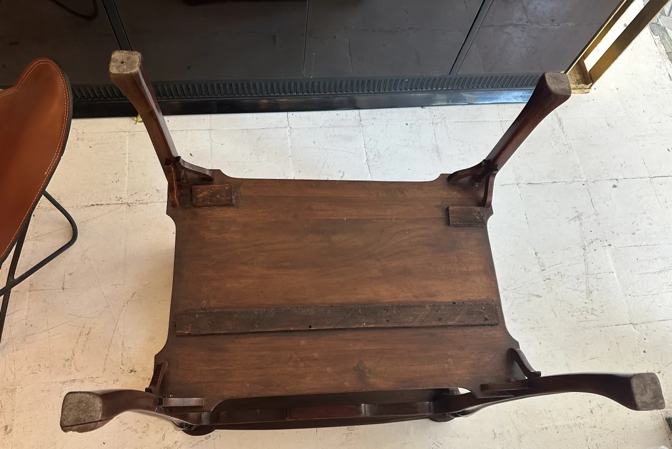 Top view of an antique small table with visible legs in a modern setting.
