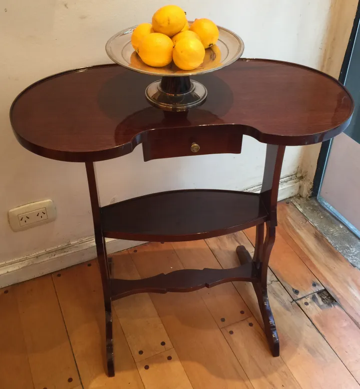 Petite table ancienne de forme ovale avec des fruits sur une assiette.