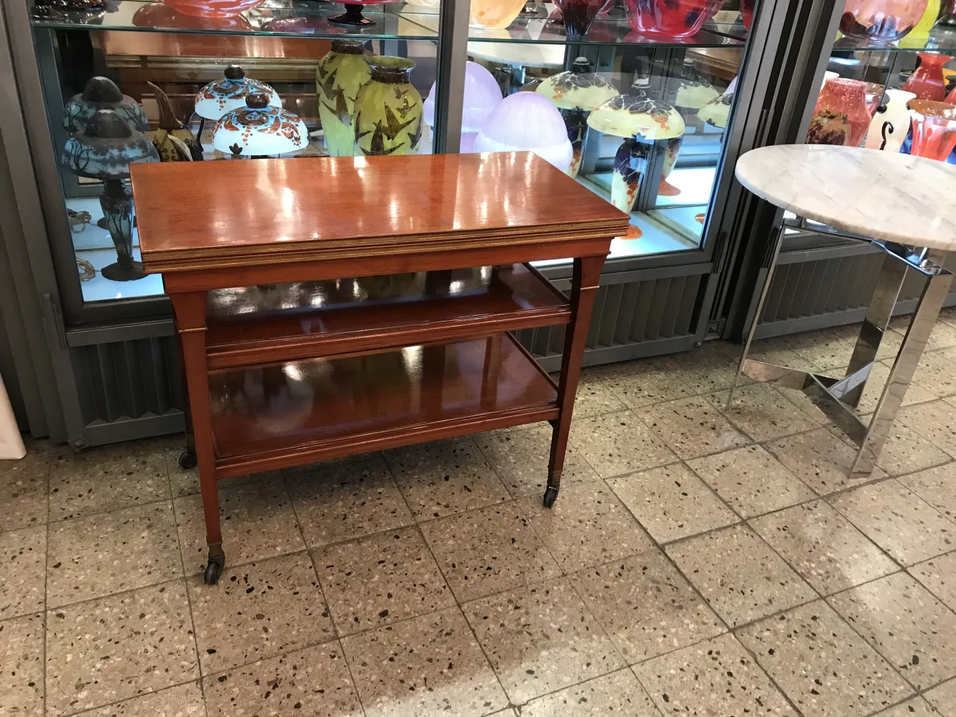 Antique small table with shelves, warm environment; varied decor.