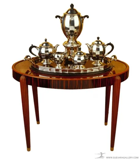 Petite table ancienne ronde avec un service à thé en argent sur le dessus.