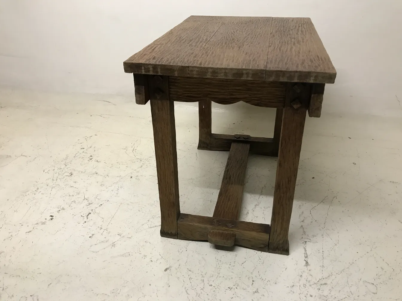 mesita antigua de forma rectangular, con patas robustas y detalles visibles, sobre fondo claro