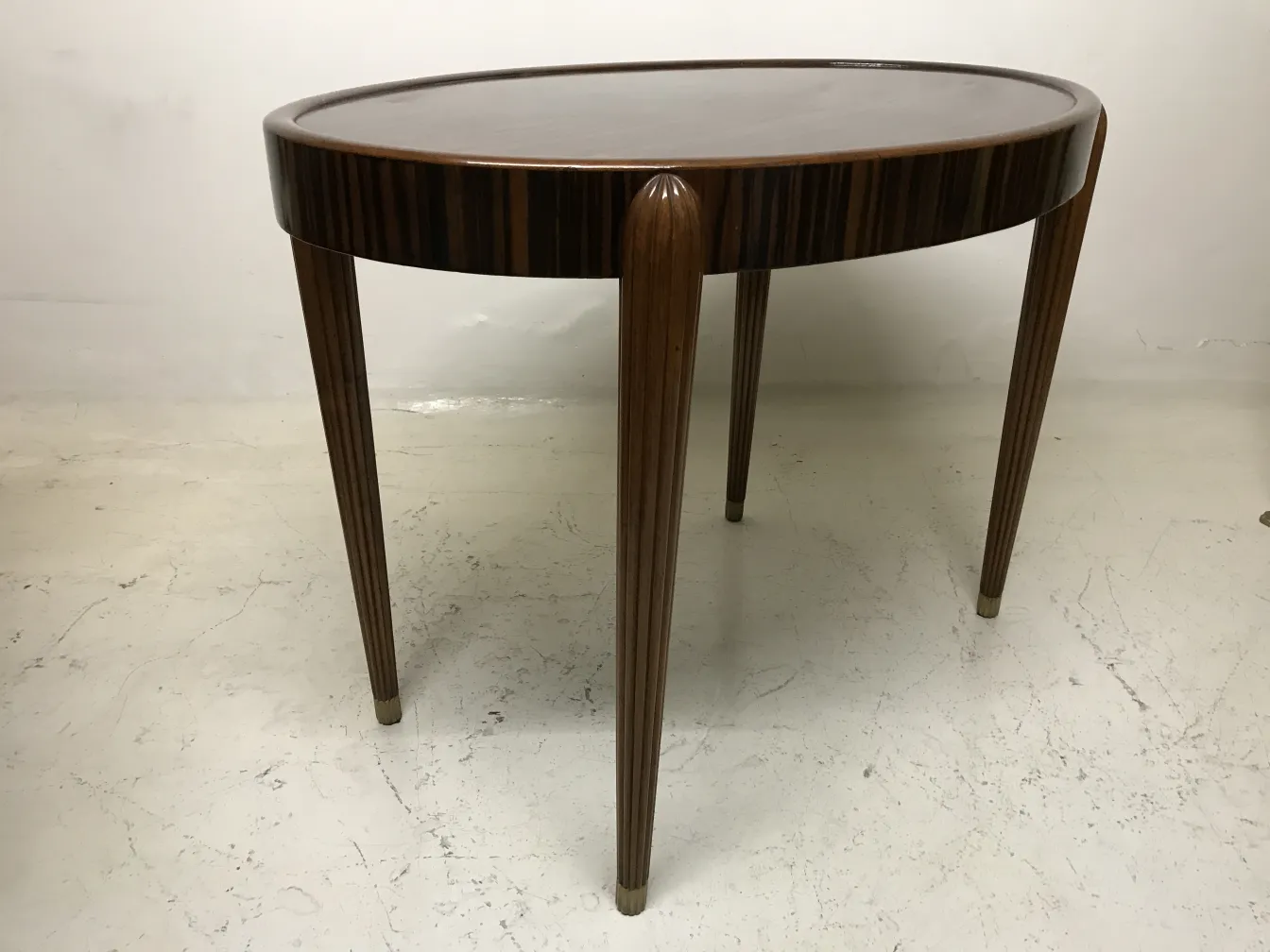 Petite table antique avec des jambes élégantes et forme ovale dans un environnement clair.