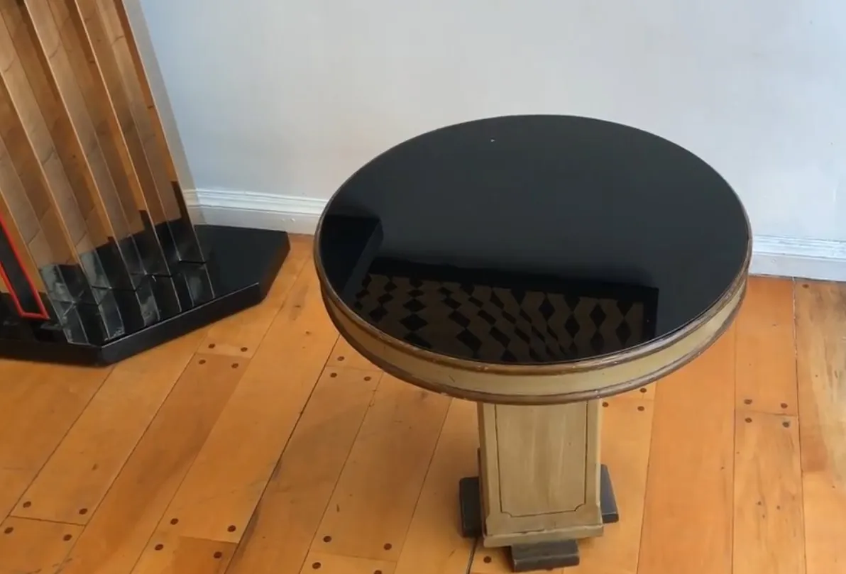 Antiker runder kleiner Tisch mit dunklem Finish, in einer gemütlichen Umgebung mit hellem Holzboden.