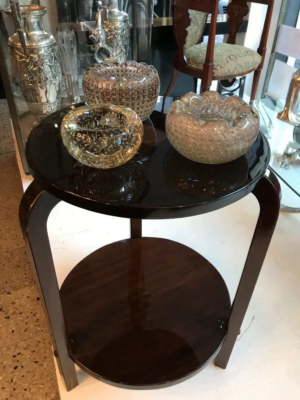 Mesinha redonda antiga com frascos de vidro decorativos.