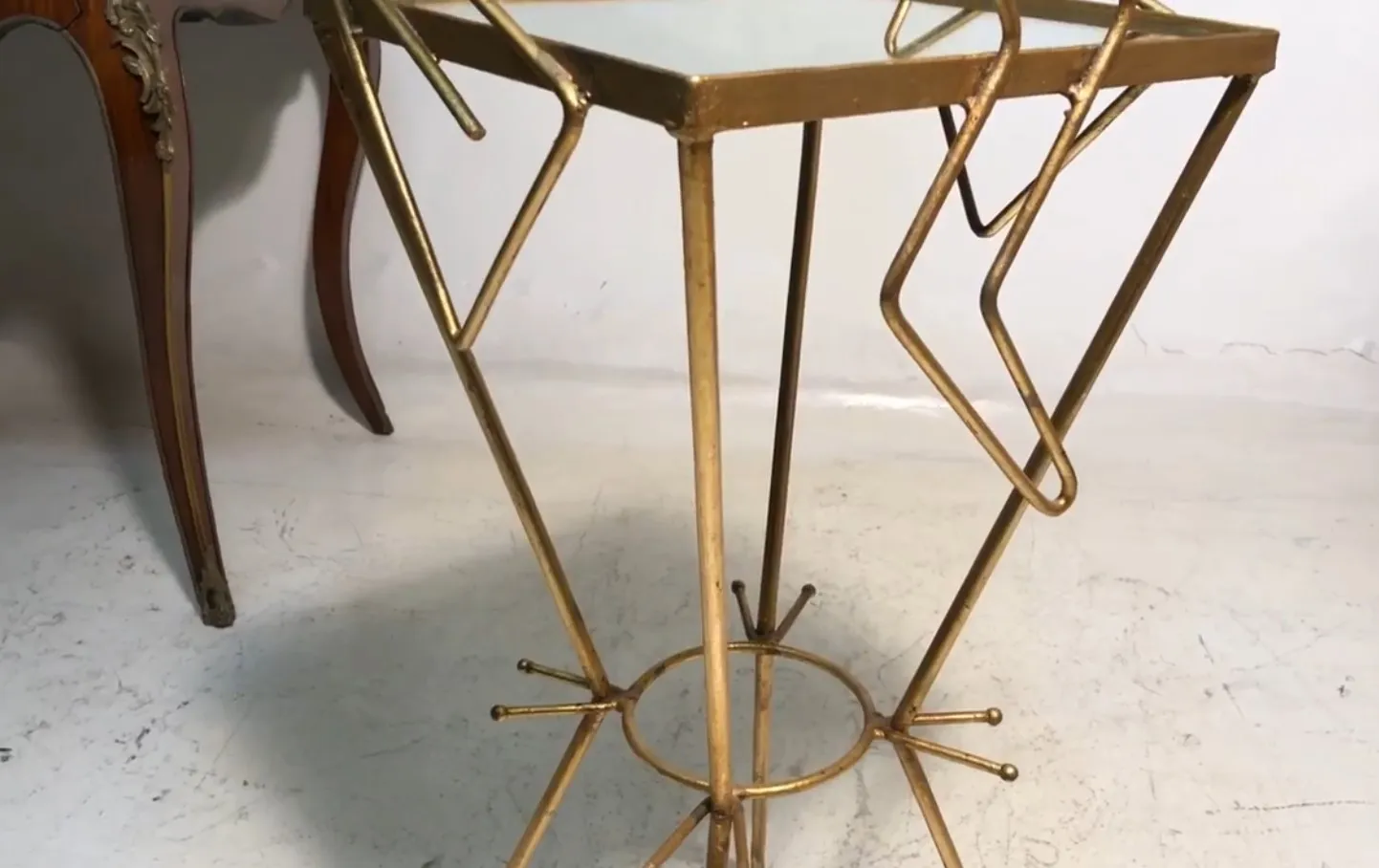 petite table au design ancien avec des pattes dorées, fond neutre