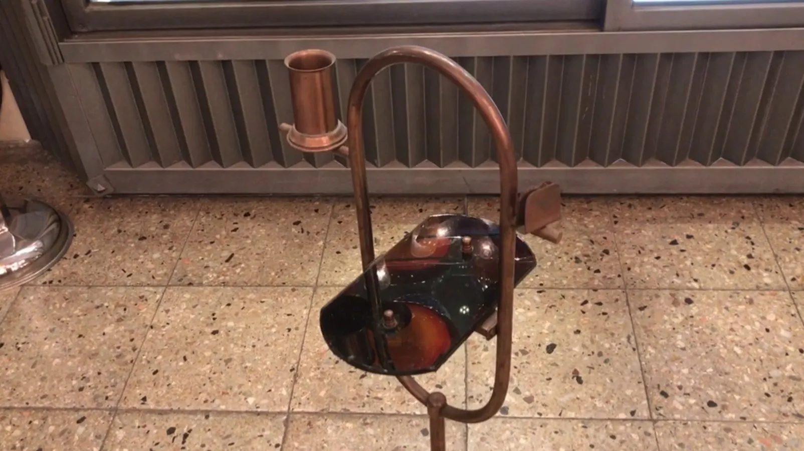 पुरानी छोटी मेज़ जिसमें एक मुड़े हुए डिज़ाइन और दीया धारक है, एक क्लासिक सेटिंग में