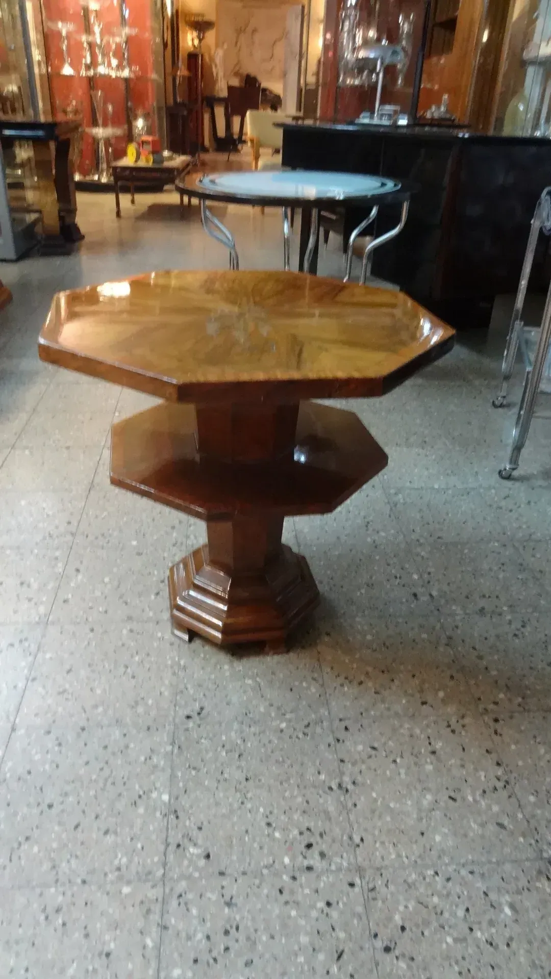 Tavolino antico di forma ottagonale con dettagli decorativi in un ambiente di antiquariato.