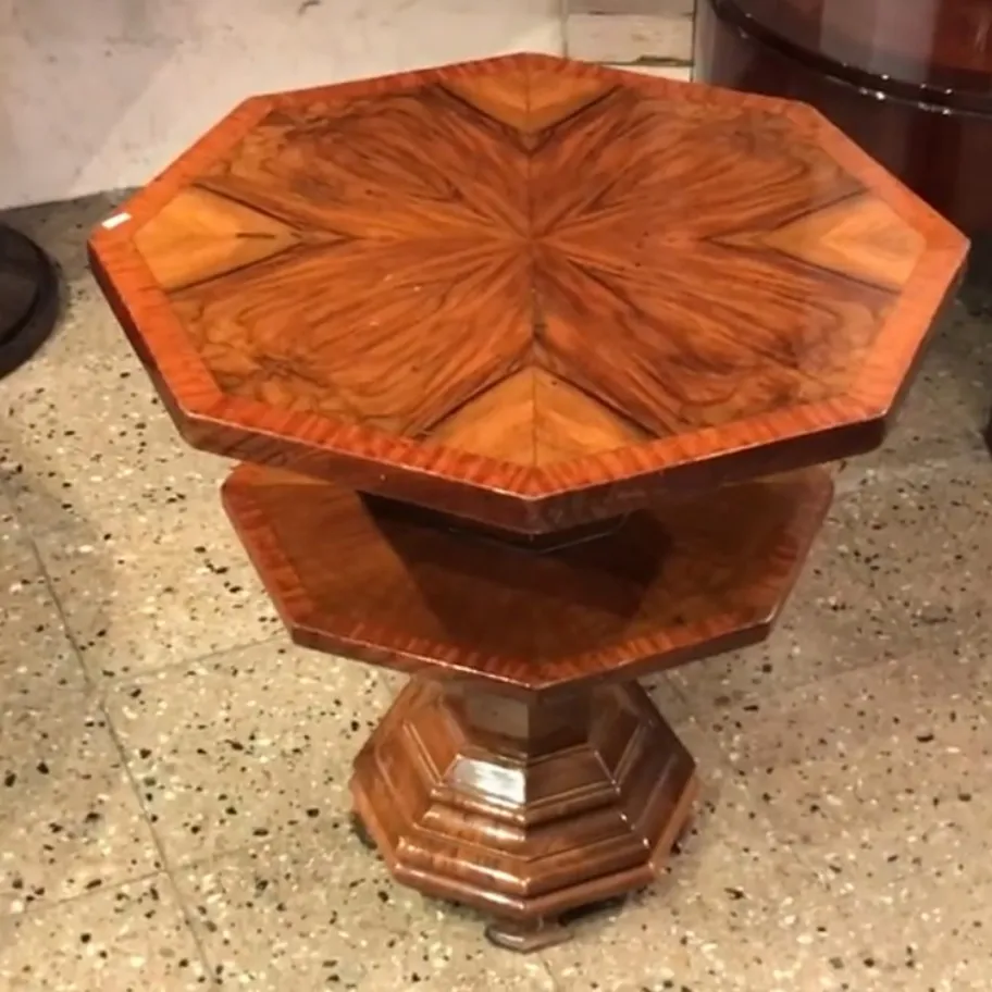 Mesita antigua octogonal con hermoso diseño en la parte superior, rodeada de un ambiente clásico.