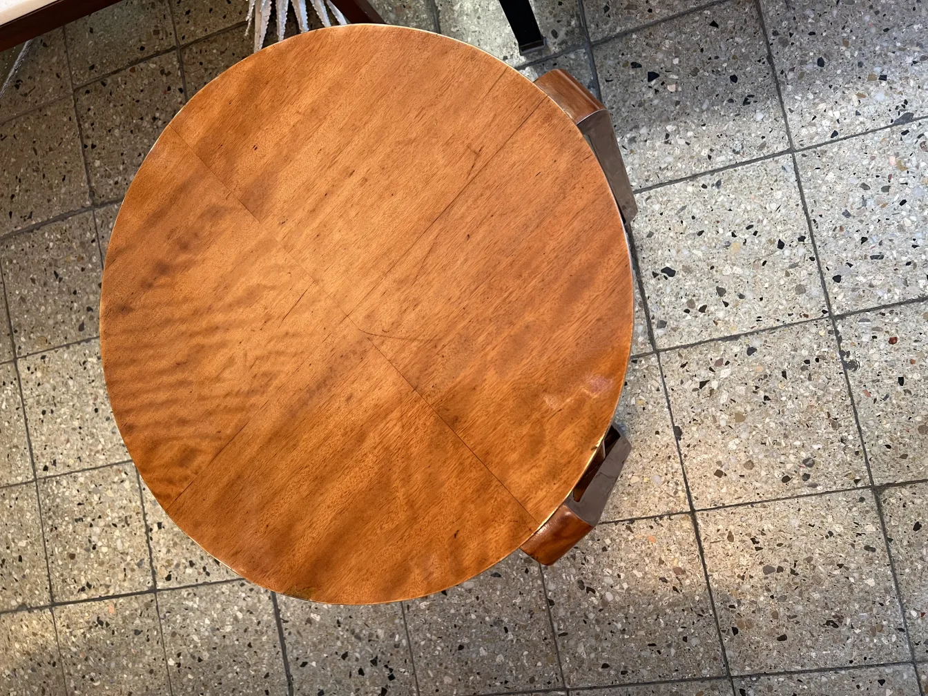 Mesita antigua redonda con superficie de madera en ambiente neutro.