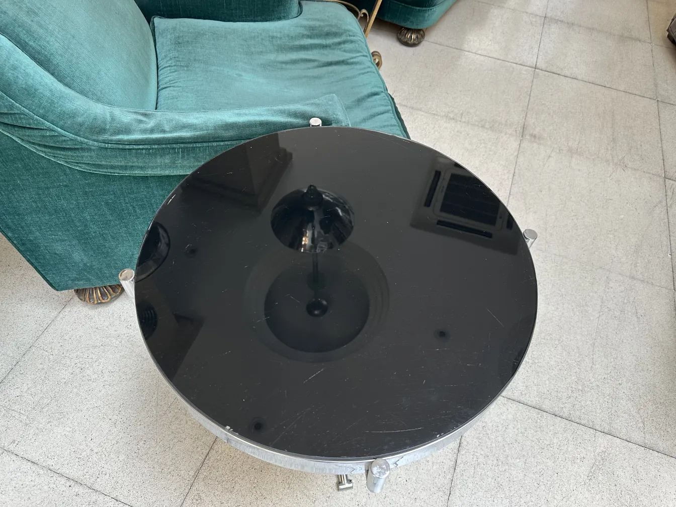 round antique small table with elegant design beside a green sofa