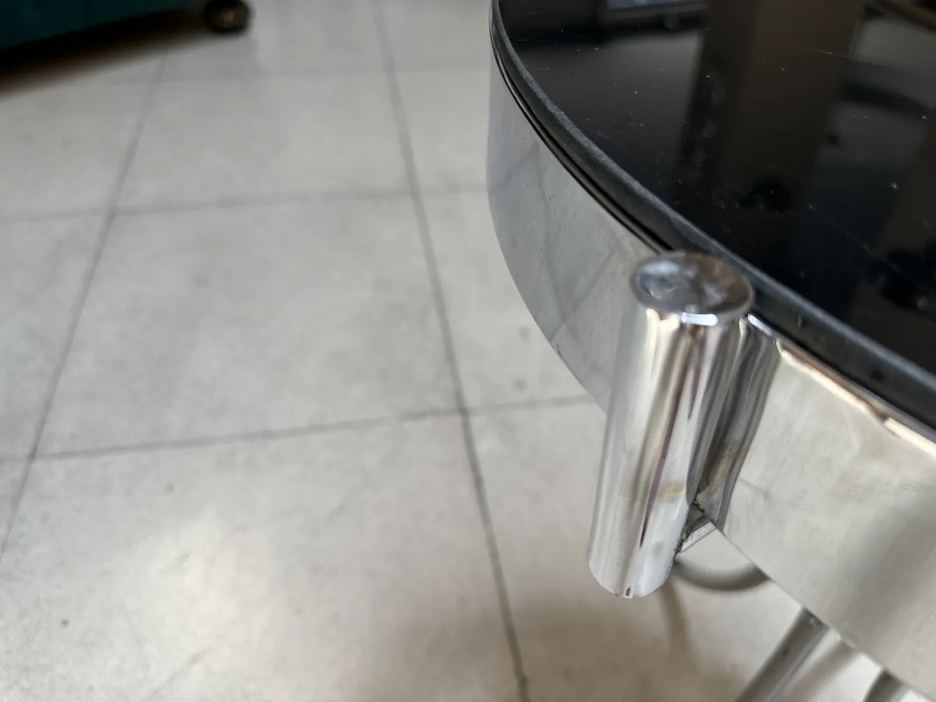 Mesinha antiga redonda com detalhes em relevo, em um ambiente neutro