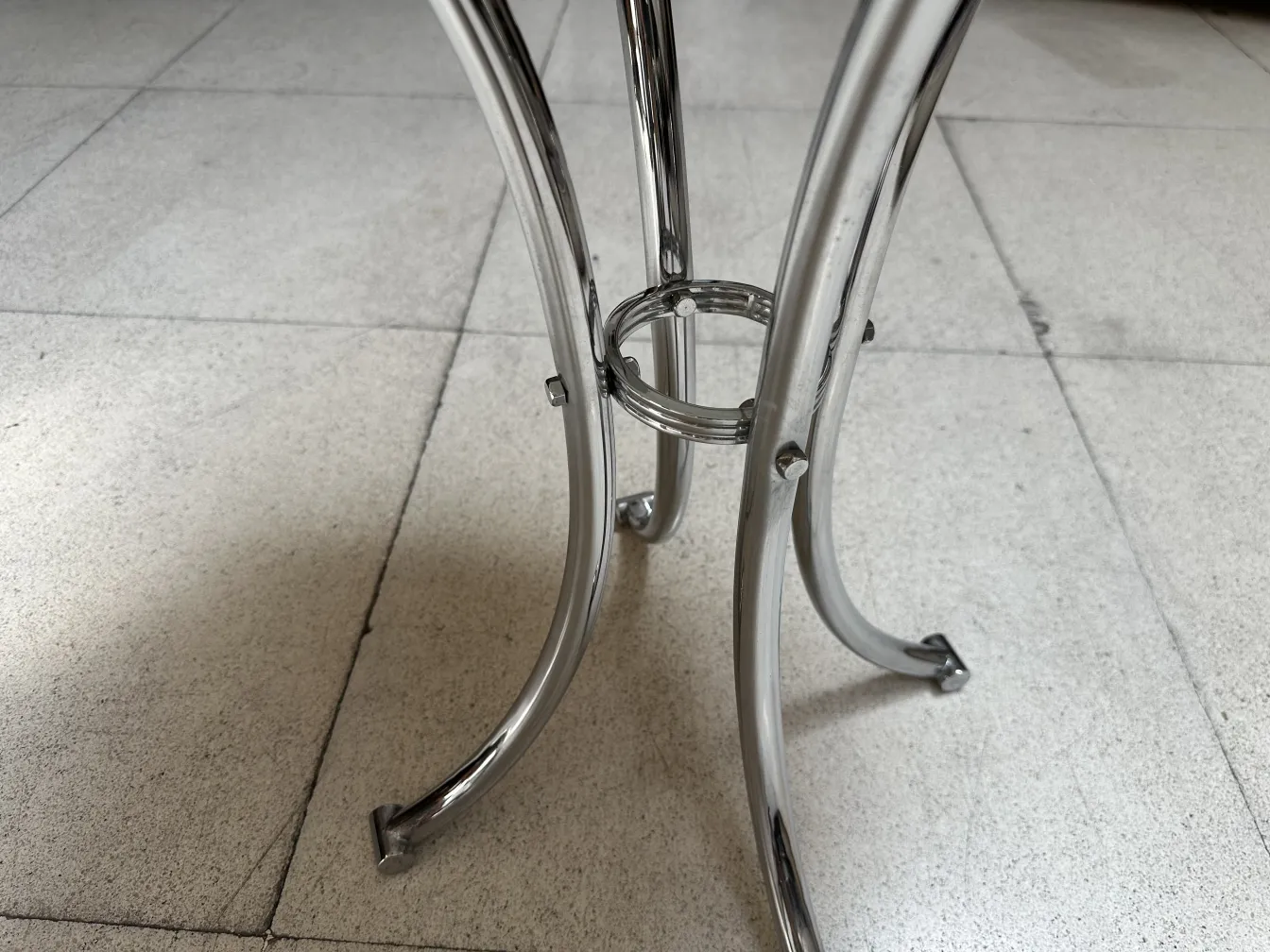 Vista de las patas curvas de una mesita antigua en un ambiente neutral.