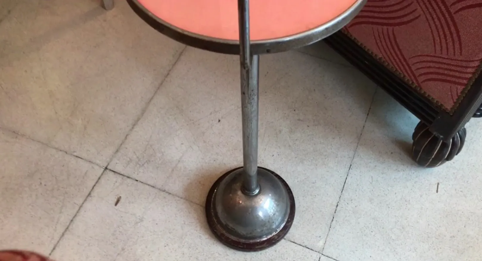 Petite table ancienne avec base ronde, couleur argentée, sur un sol clair.