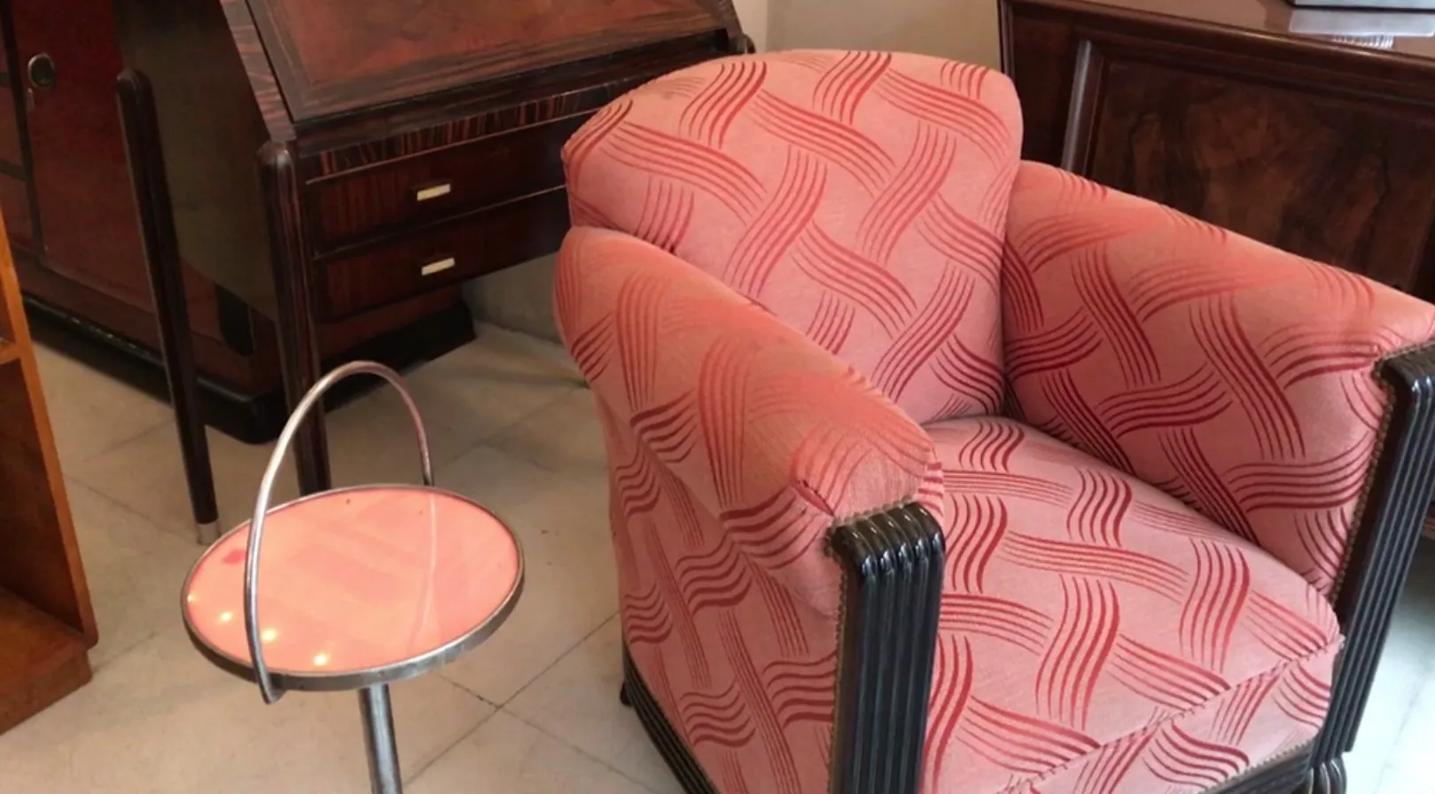 mesinha antiga pequena com design redondo e base de metal, em ambiente de antiguidades