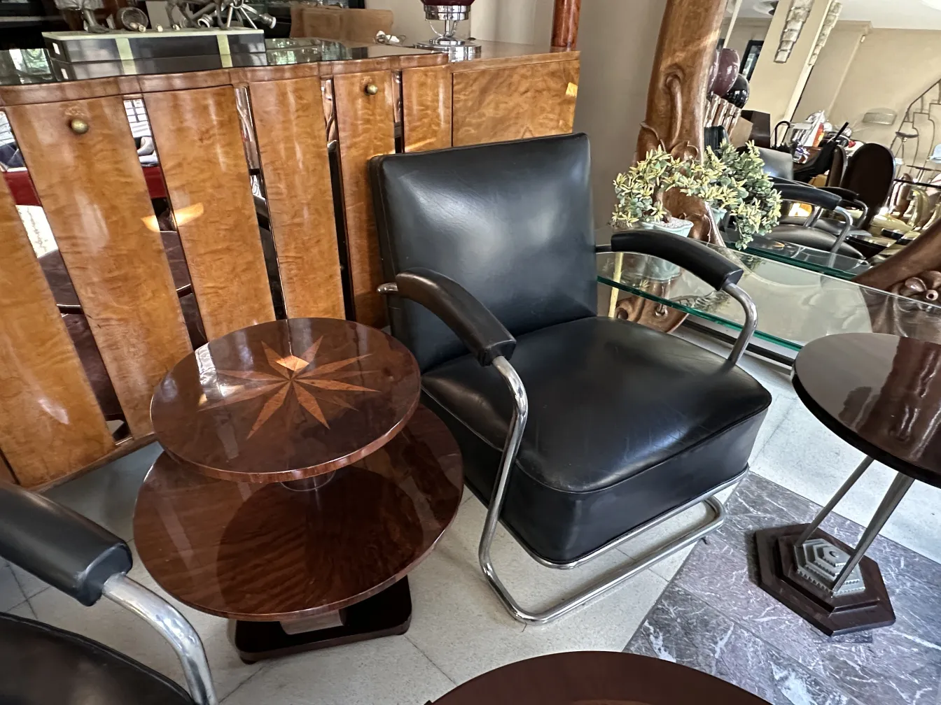 Petite table ancienne avec forme ronde et décoration en étoile, à côté d'une chaise. Ambiance accueillante avec d'autres meubles.