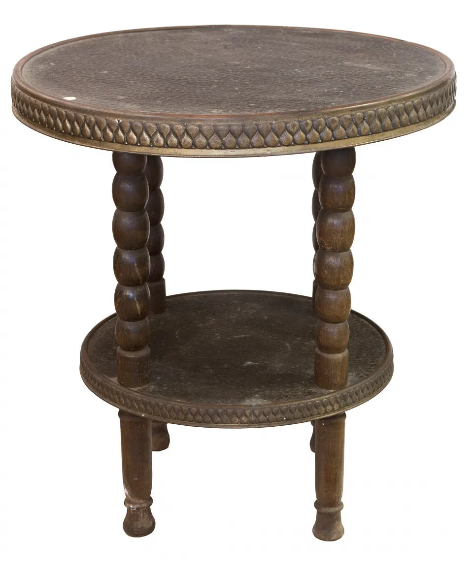 Tavolino antico con due livelli, design rotondo e gambe tornite in un'atmosfera accogliente.