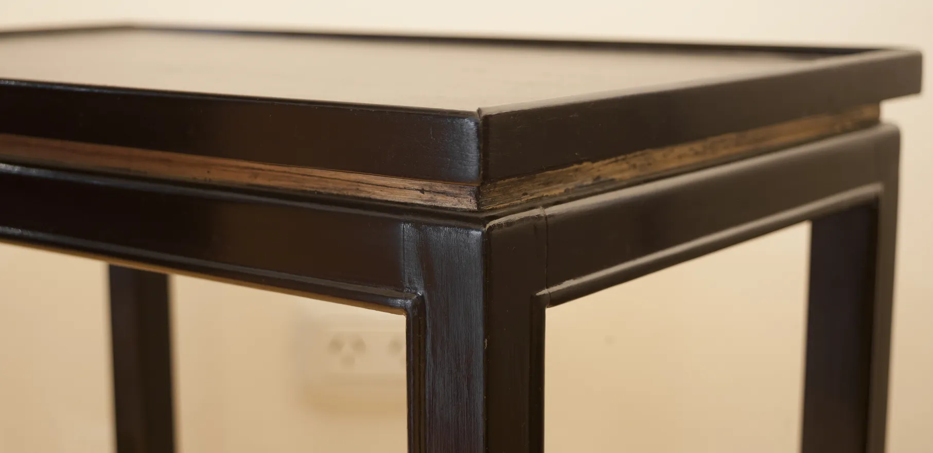 Détail d'une petite table antique avec une finition foncée et des détails de conception.