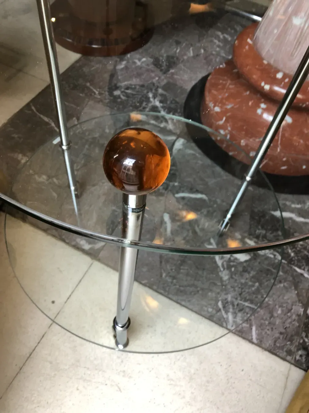 Tavolino antico con base trasparente e sfera decorativa in un ambiente moderno.