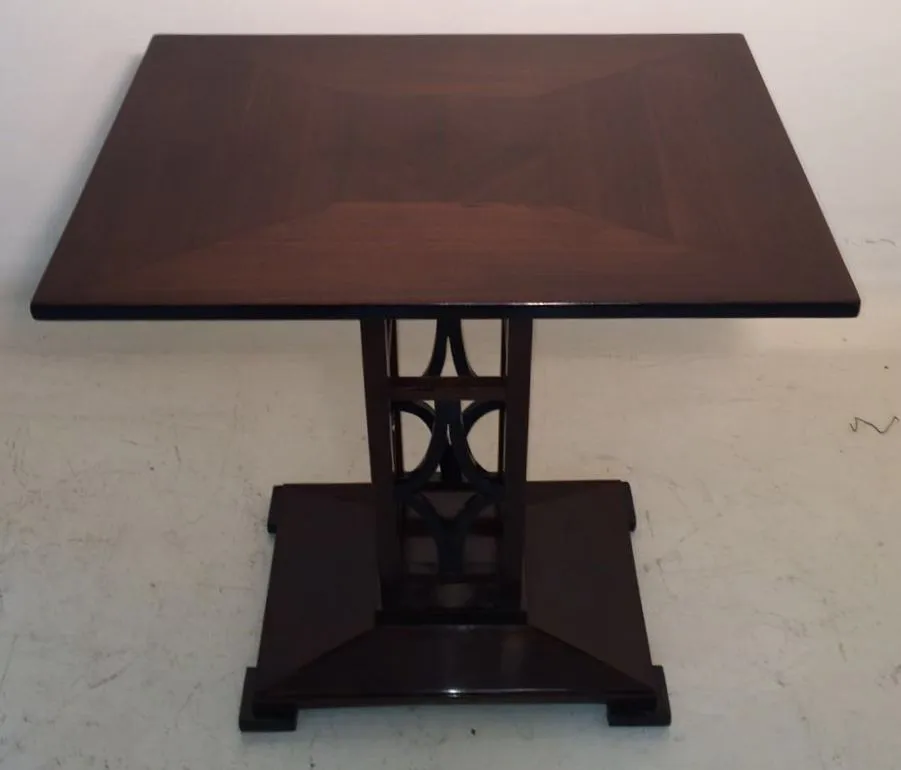 tavolino antico con design elegante alla base, in un ambiente neutro.