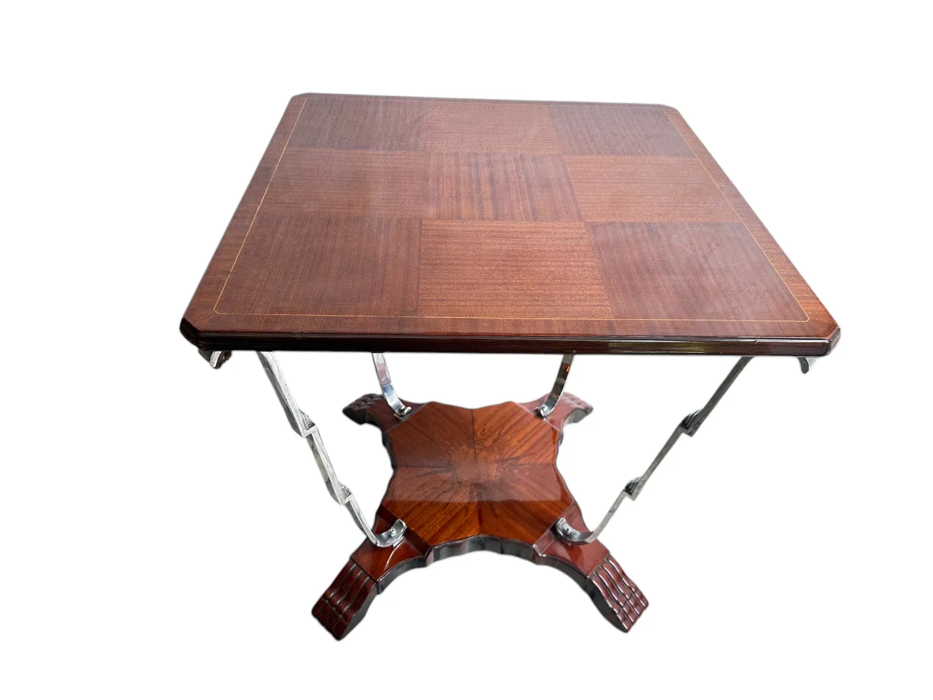 Petite table ancienne avec une surface carrée, des détails dans le design et des pieds élégants. Présentée sur un fond neutre.