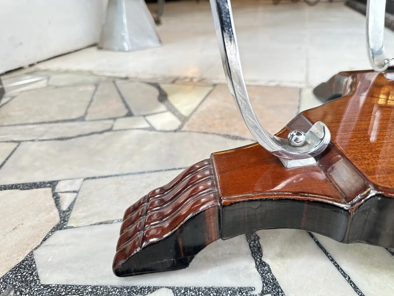 Antiker kleiner Tisch mit aufwendigem Fuß und dekorativen Details in einer gemütlichen Umgebung.