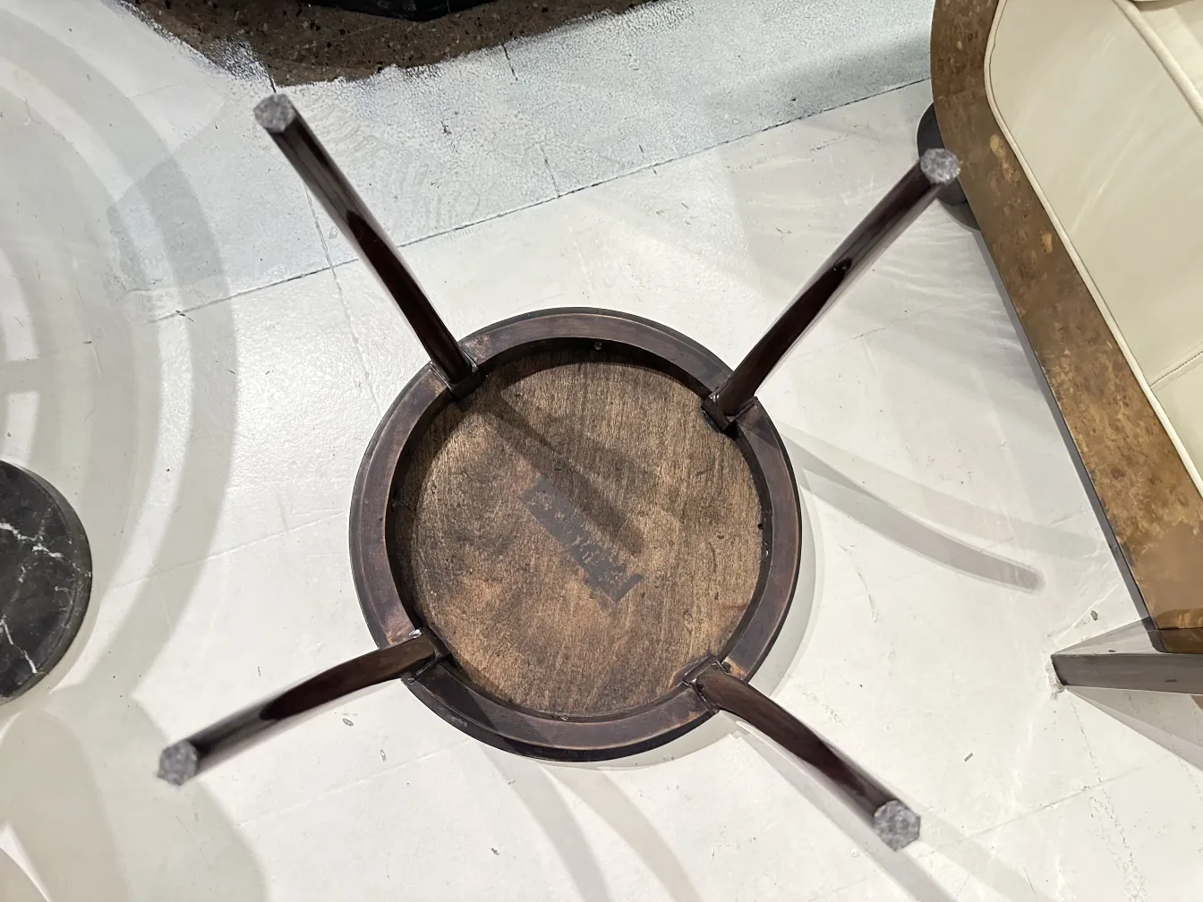 Vue du dessus d'une petite table ancienne avec des pieds courbés et un design rond, dans un environnement élégant.
