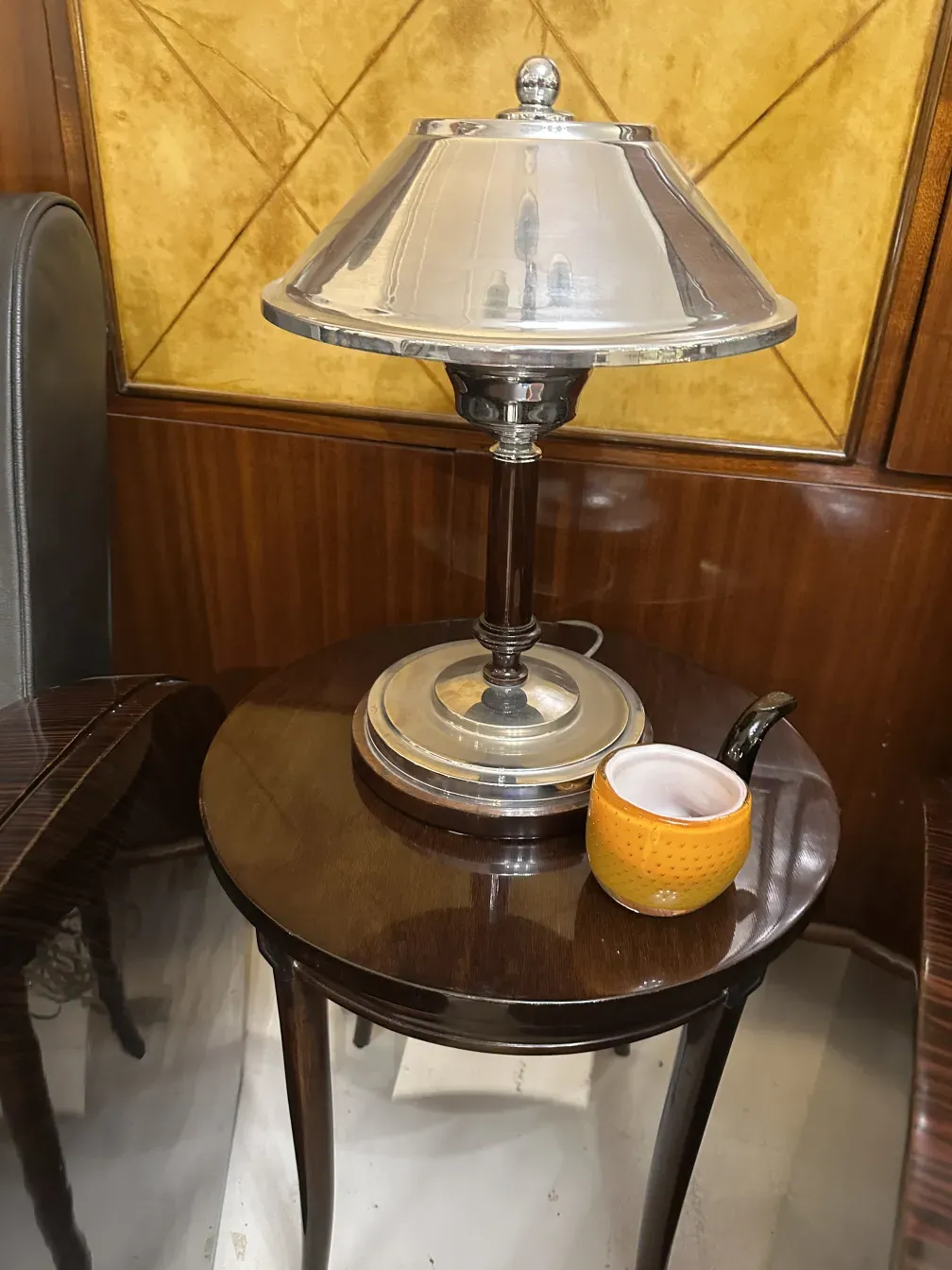 Tavolino antico con lampada e tazza gialla decorativa.