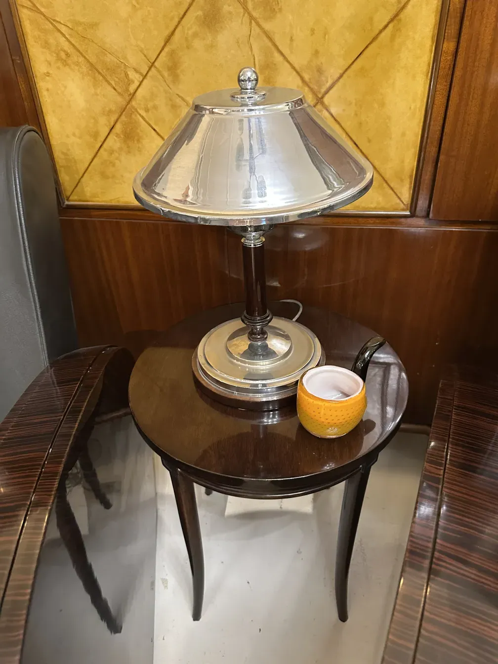 Mesita antigua decorada con una tapa y un objeto decorativo amarillo.