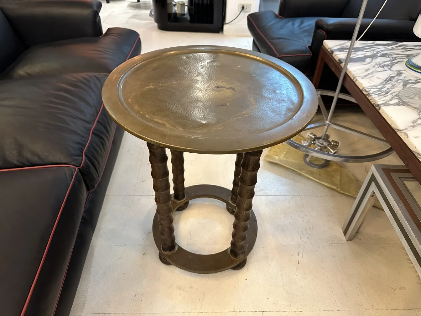 ancienne petite table avec base ronde, entourée de canapés sombres
