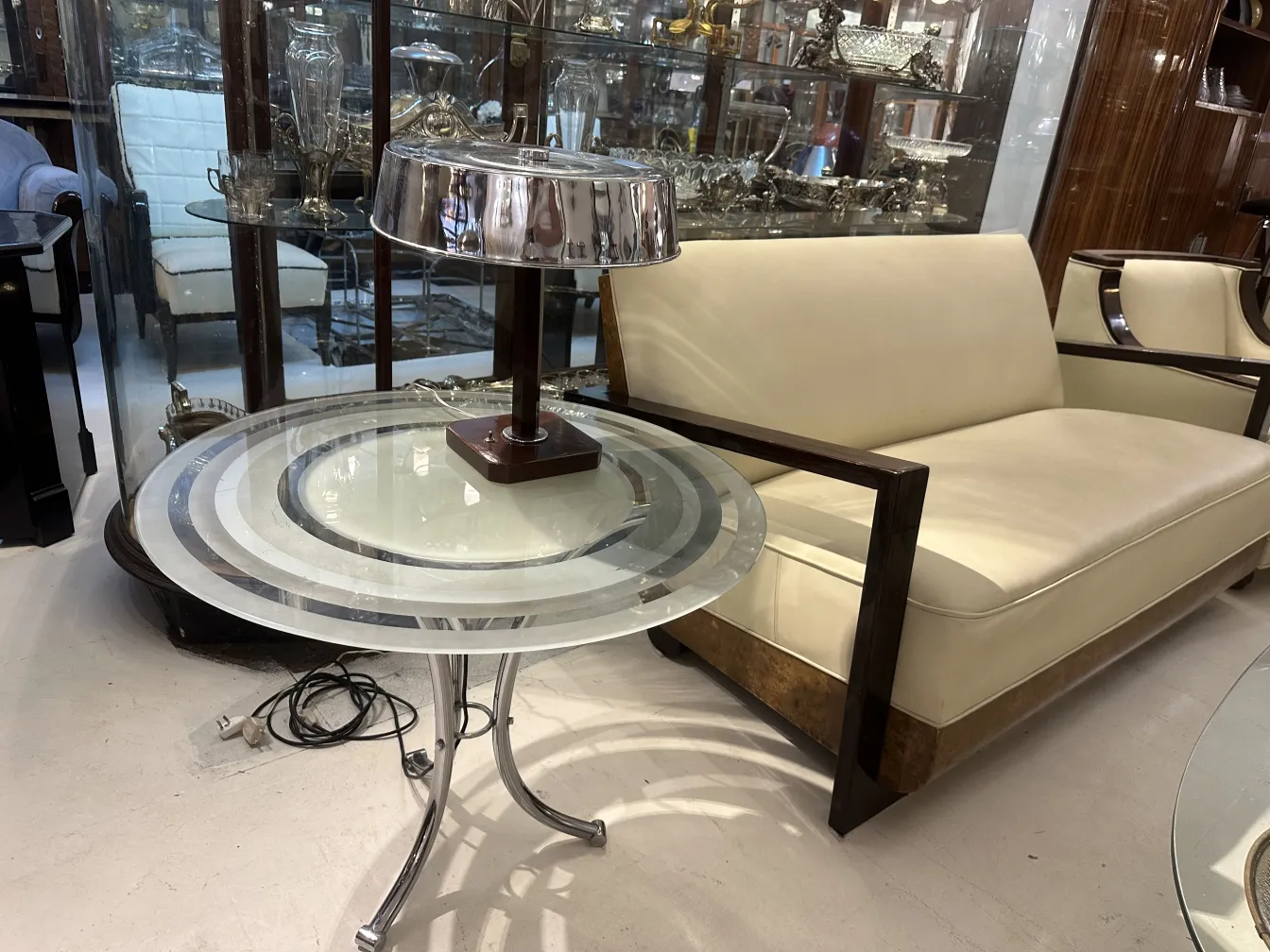 Mesita antigua con diseño elegante y base de metal, en ambiente de salon.