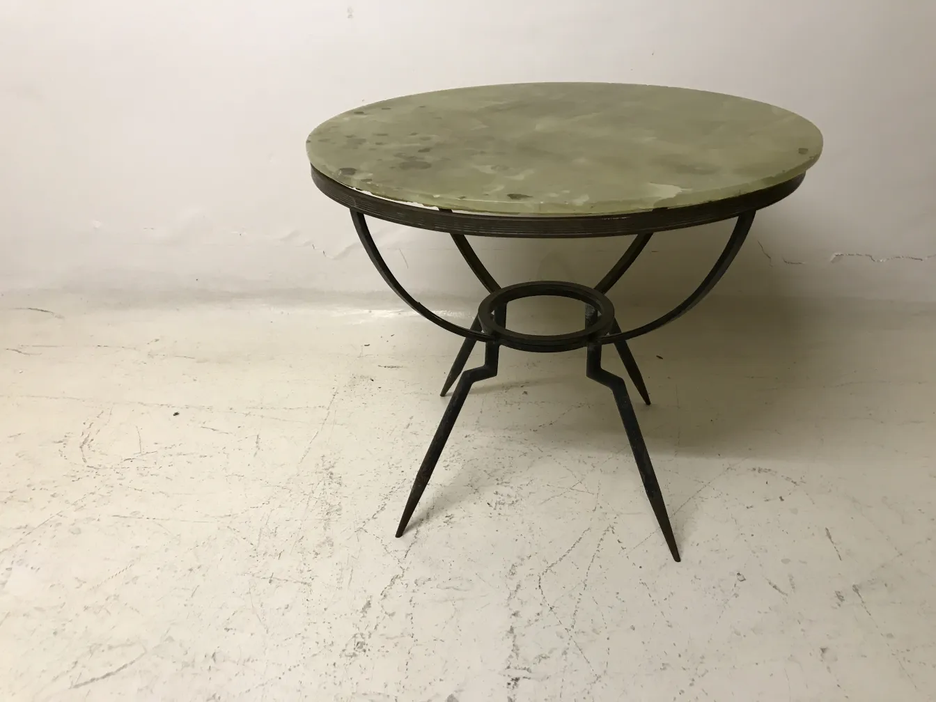 Petite table ronde avec des jambes minces sur un fond clair.