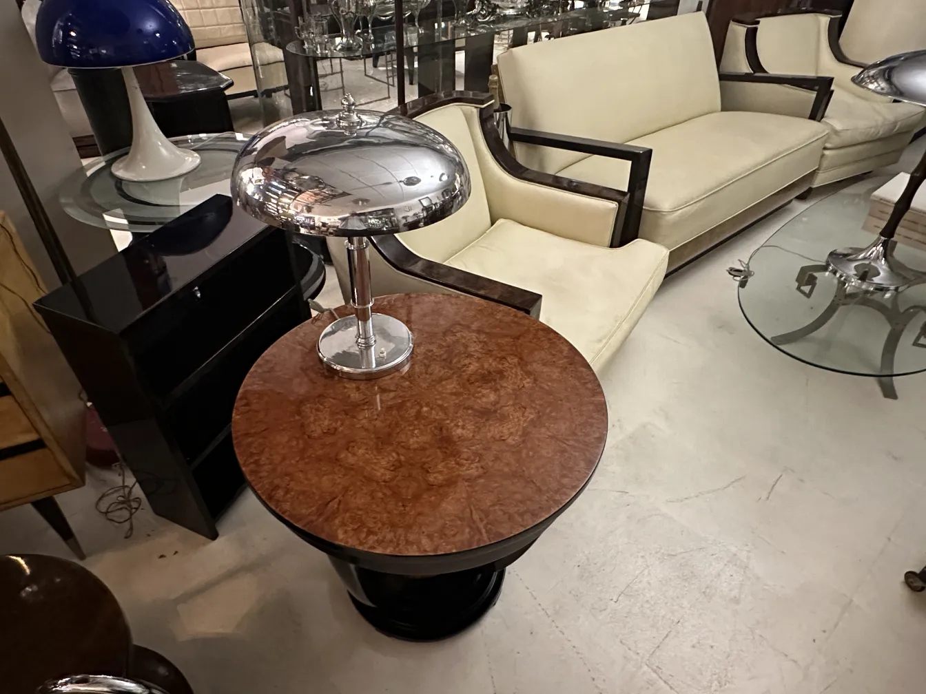 Petite table ancienne ronde avec un design décoratif en haut, entourée de meubles