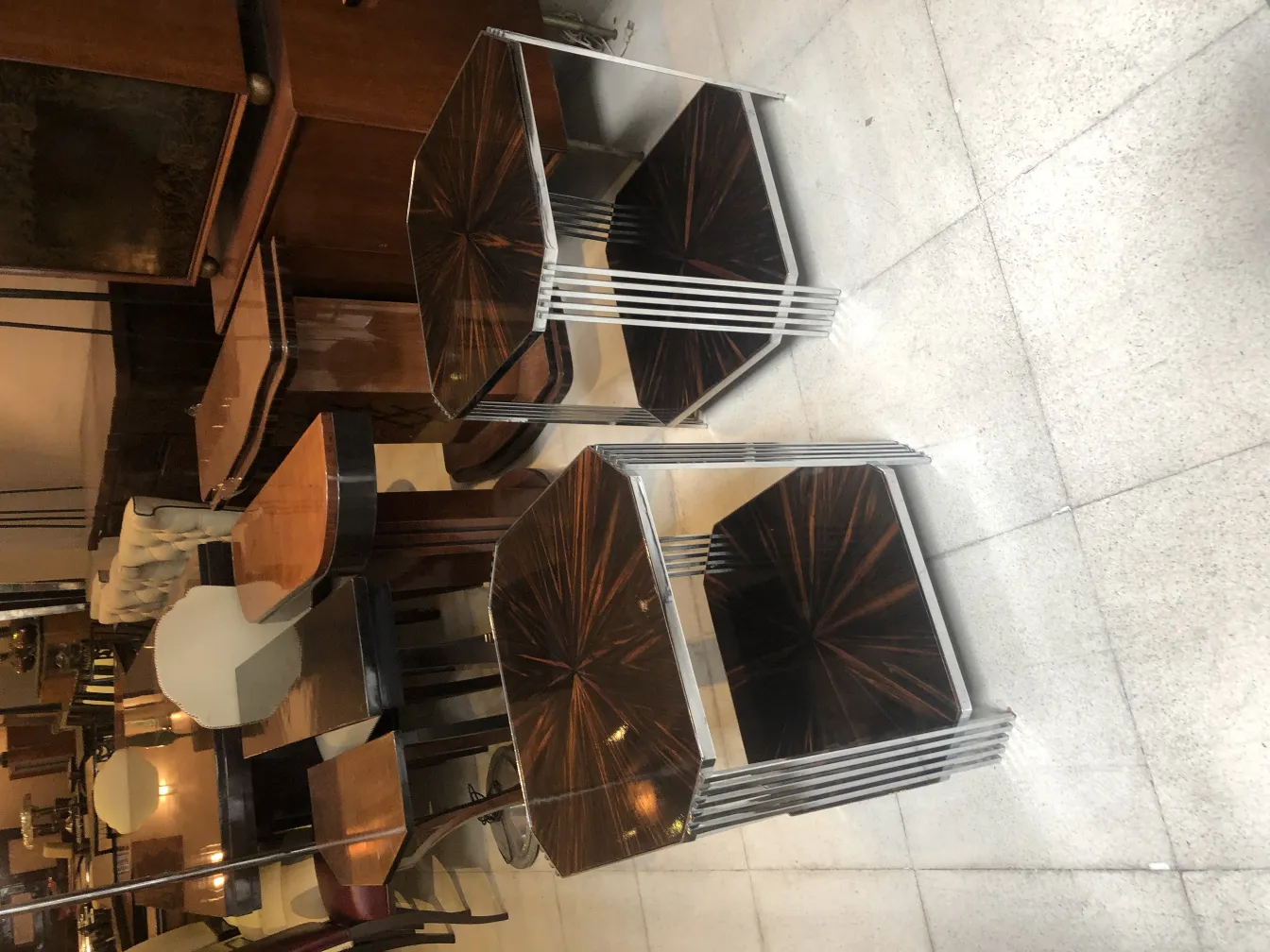 Deux petites tables anciennes dans un environnement accueillant avec d'autres meubles en arrière-plan.