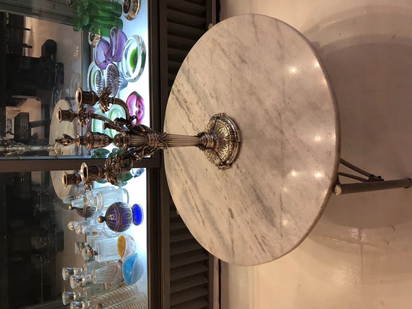 Dois candelabros antigos de estilo Art Nouveau, cercados por objetos decorativos em um ambiente elegante.