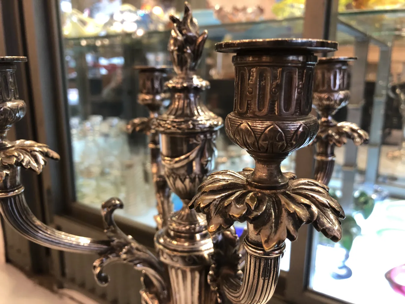 葉や花のディテールがある二つの燭台、背景にガラス製品