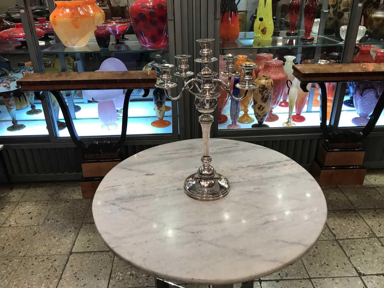 Two antique candelabras with an elegant design on a marble table.