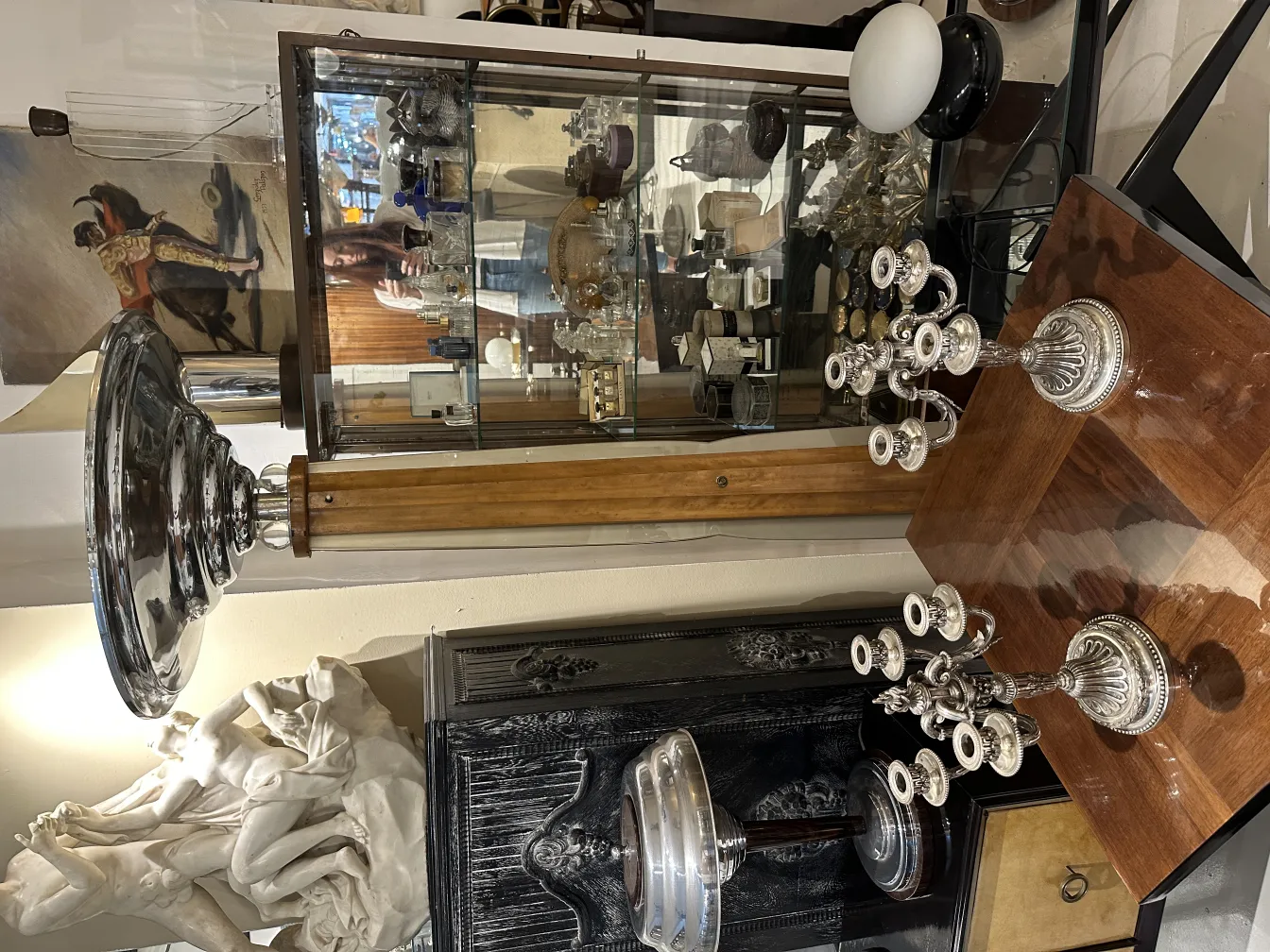 Due portacandeli antichi in un ambiente elegante con dettagli decorativi e una varietà di oggetti antichi.