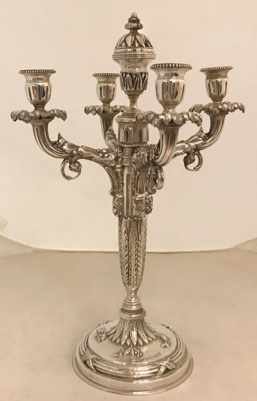 Castiçais antigos com múltiplos braços e detalhes decorativos, em um ambiente neutro.